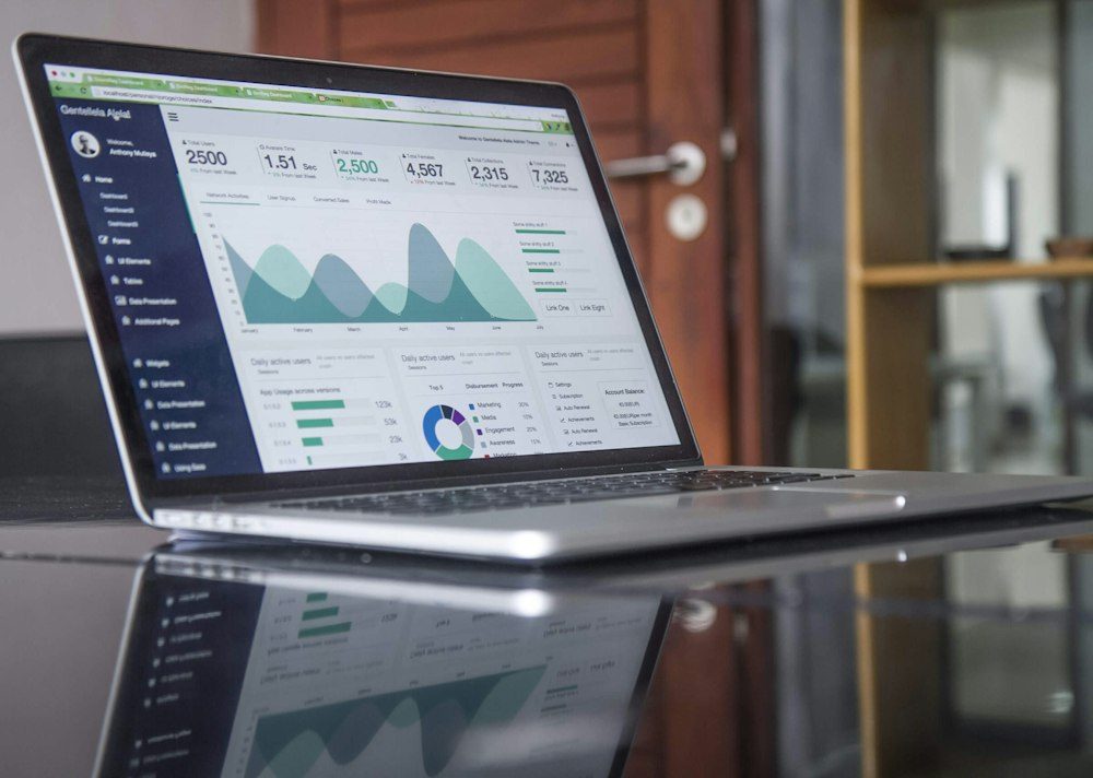 Notebook aberto sobre a mesa, exibindo um painel de indicadores e gráficos
